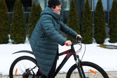 Yaşlı bir kadın şehirde bisiklet sürerken pedal çeviriyor..