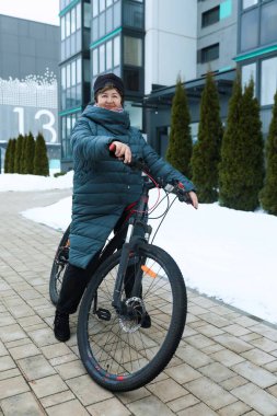 Spor yapan ve sokakta bisiklet süren yaşlı bir kadın..