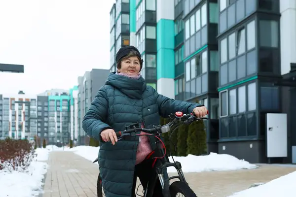 Healthy pensioner woman leads a healthy lifestyle and rides a bike in winter.