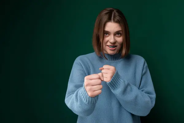 stock image A woman is wearing a blue sweater and is shown making a fist gesture with her hand. She appears determined and focused.