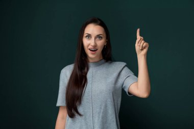 Bir kadın işaret parmağıyla bir objeyi işaret ediyor. Başka birine bir şey gösteriyor ya da özel bir nesneye dikkat çekiyor gibi görünüyor. Bu jest kasıtlı ve doğrudan..
