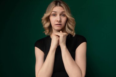 Elleri çenesinde dinlenen, ayakta duran bir kadın. Uzaklara bakarken bir şeyi derin derin düşünüyor ya da düşünüyor gibi görünüyor..