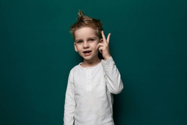 Genç bir çocuk, parmaklarıyla barış işareti hareketi yaparken görülüyor. Çocuk neşeli ve kaygısız görünüyor. Genellikle barış ve barış ile ilişkili V şeklindeki el işaretini şakayla gösteriyor.