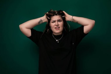 Saçları ve ellerine odaklanmış bir şekilde saçlarını başının önünde tutan bir kadın görülüyor. Saç stilini inceliyor ya da düzeltiyor gibi görünüyor..