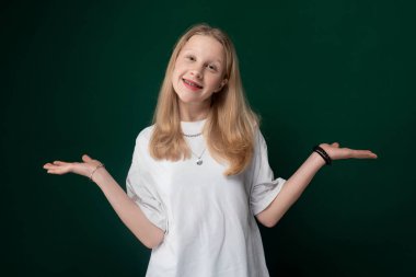 Bir kadın ellerini kameraya doğru uzatmış, yüzünde parlak bir gülümseme ile ayakta duruyor. Önündeki herkesi karşılarken vücut dili sıcaklık ve açıklık yayıyor..