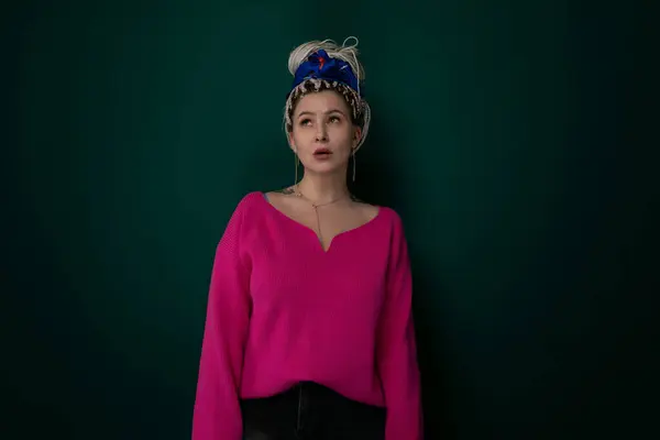 ピンクのセーターの女性は カジュアルなポーズに立って青い帽子をかぶっています — ストック写真