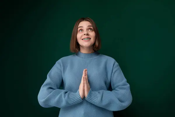 Kobieta Niebieskim Swetrze Stoi Przed Tętniącą Życiem Zieloną Ścianą Patrząc — Zdjęcie stockowe