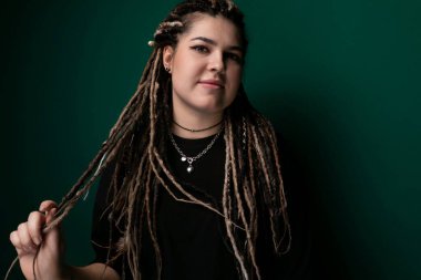 Rasta bukleli bir kadın elinde bir makas tutuyor, kullanmaya hazır. Makas açık görünüyor ve elindeki işe odaklanmış gibi görünüyor..