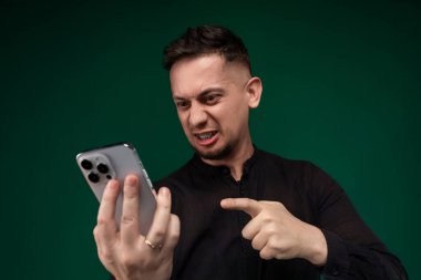 Bir adam sağ elinde bir cep telefonu tutuyor. Ekrana dikkatle bakıyor gibi görünüyor, muhtemelen internete mesaj atıyor ya da internette geziniyor..