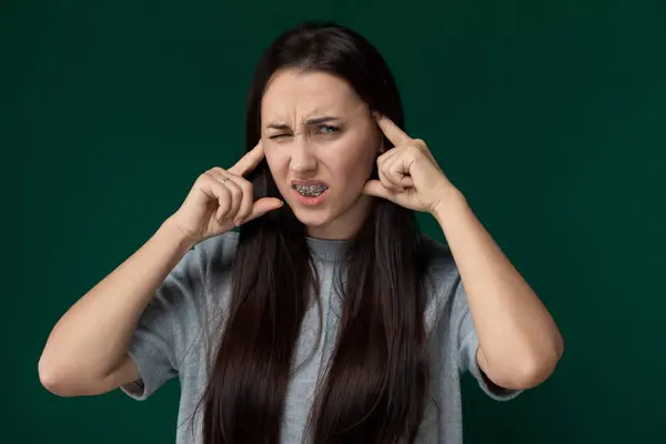 stock image A woman is shown holding her head with both hands, looking distressed or overwhelmed. She appears to be in deep thought or experiencing intense emotions.