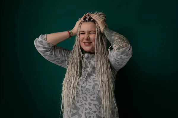 Stock image A woman with long flowing hair is smiling brightly while holding both hands on top of her head in a gesture of joy and excitement. Her eyes are sparkling with happiness as she exudes a sense of