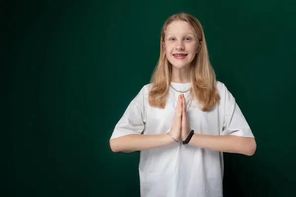 stock image A woman is standing in front of a solid green wall. She appears to be looking straight ahead, with a neutral expression on her face. The wall provides a simple backdrop for the womans presence.