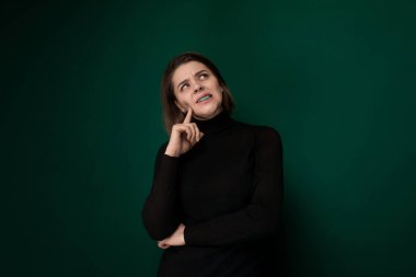 Siyah gömlek giyen bir kadın fotoğraf için poz veriyor. Rahat bir ifadeyle kendine güvenerek duruyor, kıyafetini sergiliyor. Geçmişi basit, onun odak noktası olmasına izin vermek.