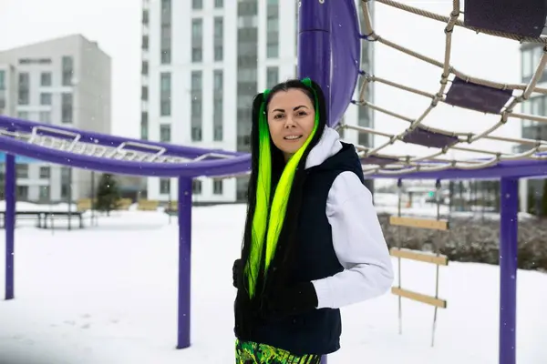 stock image A woman in front of a purple and purple structure, looking at the camera. The structure has modern, angular designs and stands out against the sky.