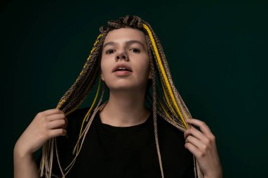 A woman with dreadlocks is standing upright in front of a vivid green background. Her hair is styled in long, thick dreadlocks that cascade down her back. She is looking confidently at the camera clipart