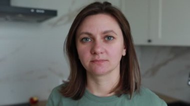 Sakin ve huzurlu bir kadın, aydınlık, modern bir mutfakta, doğal ışığın aktığı sakin bir bahar sabahı için rahatlatıcı bir atmosfer sağlıyor..