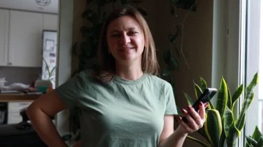 Bir kadın mutfakta elinde bıçakla dikilirken görülüyor. Bıçağı güvenli bir şekilde tutarken odaklanmış ve kararlı görünüyor. Mutfak geçmişi tipik bir ev ortamını gösteriyor..