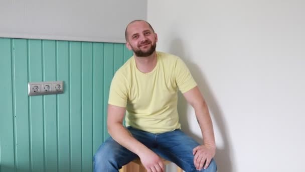 Ein Glatzköpfiger Mann Einem Gelben Shirt Sitzt Lässig Vor Einer — Stockvideo
