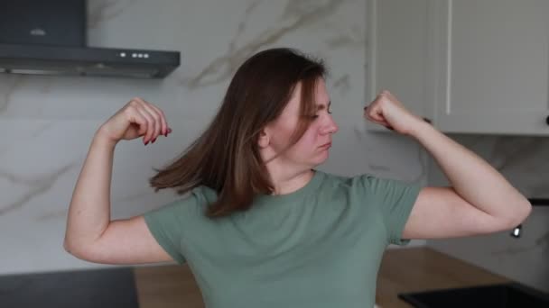 カジュアルなTシャツの女性は 大理石と現代のキッチンの限界内で基本的なトレーニングルーチンを披露するために柔軟かつ伸びる一連の腕のエクササイズを実行することが示されています — ストック動画