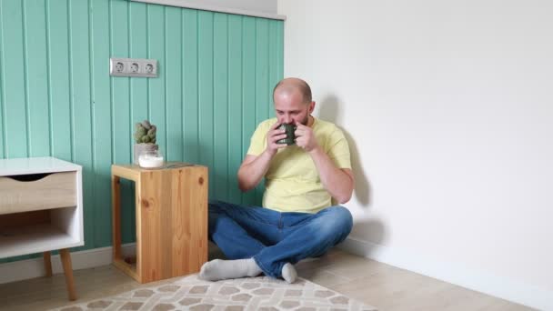 Ein Glatzköpfiger Mann Gelbem Shirt Und Blauer Jeans Sitzt Bequem — Stockvideo