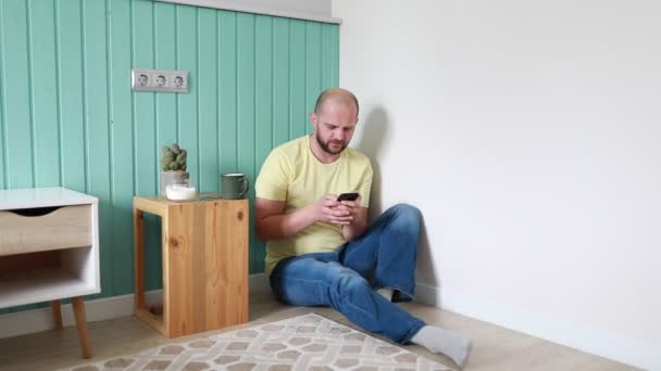 Bald Man Yellow Shirt Sits Cross Legged Floor Light Blue — Stock Video
