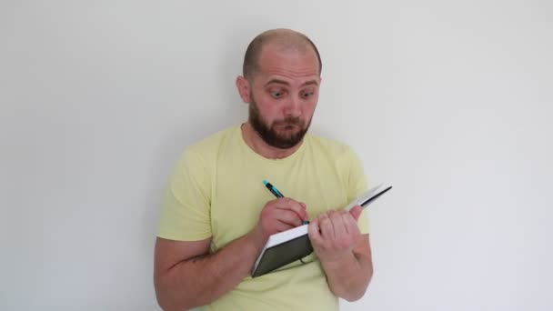 Bald Man Wearing Yellow Shirt Expresses Surprise Looks Taking Notes — Stock Video