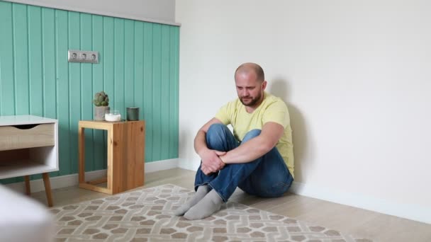 Ein Glatzköpfiger Mann Mit Gelbem Shirt Und Blauer Jeans Sitzt — Stockvideo