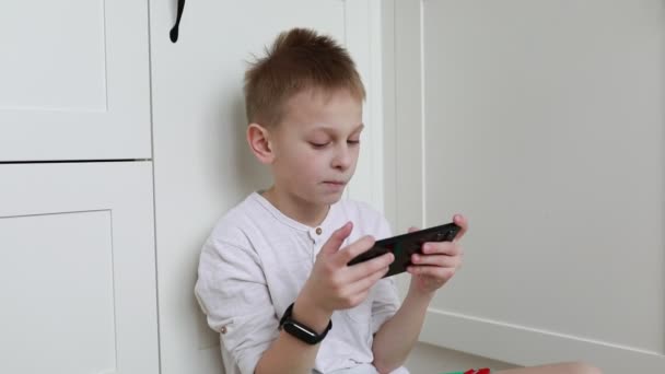 Сосредоточенный Мальчик Удобно Сидит Стены Внимание Полностью Захвачено Портативным Игровым — стоковое видео