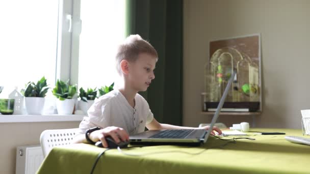 Menino Está Sentado Uma Mesa Envolvido Com Computador Portátil Ele — Vídeo de Stock