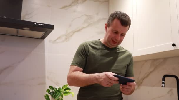 Een Man Een Casual Groen Shirt Bezig Met Zijn Smartphone — Stockvideo