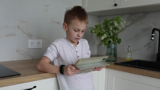 Young Boy Standing Kitchen Engrossed Reading Book Focused Attentive Flips — Stock Video