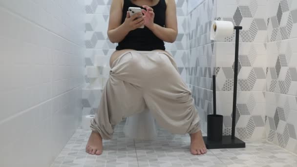 여성은 휴대폰을 사용하는 화장실에 앉아있다 그녀는 그녀의 전화에 Engrossed 스크롤 — 비디오