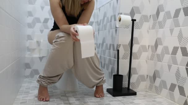 여성은 타일과 현대적인 욕실에서 화장실에 앉아있는 화장지 변경하는 행동에 표시됩니다 — 비디오