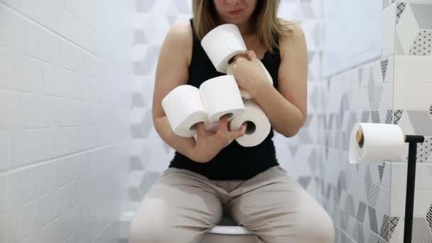 Женщина Сидит Унитазе Держа Три Рулона Туалетной Бумаги Похоже Ванной — стоковое видео