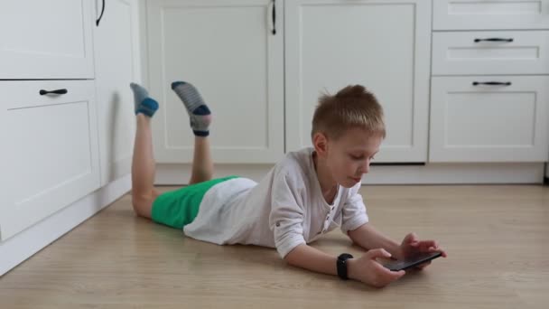 Młody Chłopiec Leży Podłodze Pochłonięty Telefonem Komórkowym Skupia Się Ekranie — Wideo stockowe