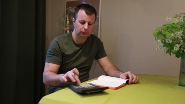 Hombre Enfocado Está Sentado Una Mesa Comedor Usando Una Calculadora — Vídeo de stock