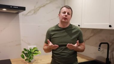 Çağdaş bir mutfak ortamında yemek pişirme tavsiyelerini hevesle paylaşan bir adam. Anlamlı el hareketleri ve çekici tavırlarıyla mermer tezgahın aşçılığına bilgelik katıyor.