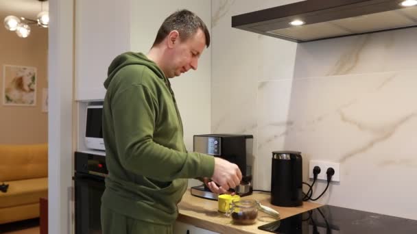 一个穿着绿色帽衫的男人正在厨房里积极地准备食物 他专注于切菜 搅拌锅和检查烤箱 厨房灯火通明 井井有条 — 图库视频影像