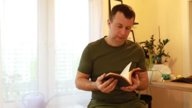 Sandalyeye oturmuş kitap okumaya dalmış bir adam var. Sayfaları çevirir, ara sıra içeriği düşünmek için duraksar. Çevre basittir, sadece adama ve onun adamına odaklanır.