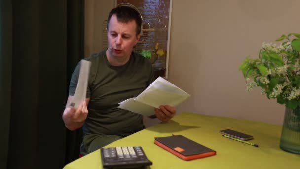 Ένας Εστιασμένος Άνθρωπος Κάθεται Στο Τραπέζι Του Στο Σπίτι Εξετάζοντας — Αρχείο Βίντεο