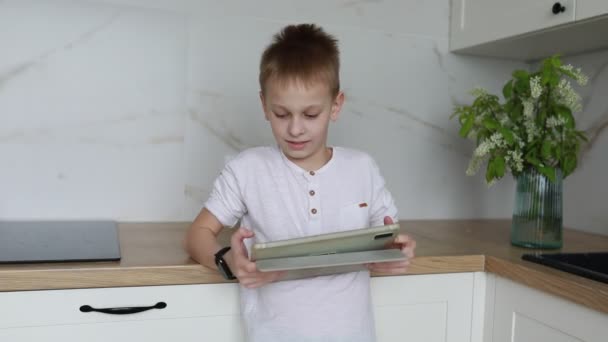 Young Boy Stands Contemporary Kitchen Focused Intently Tablet Holds His — Stock Video