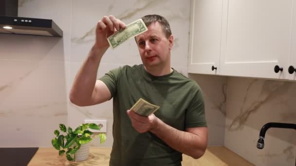 Man Stands Well Lit Kitchen Counter Methodically Counting Stack Bills — Stock Video