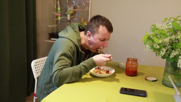 남자가 노란색 식탁보로 덮여있는 테이블에 앉아서 식사를 맛보았습니다 신선한 꽃다발이 — 비디오