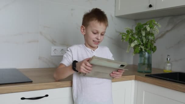 Мальчик Стоящий Кухне Внимательно Глядя Лист Бумаги Столешнице Кажется Сосредоточенным — стоковое видео