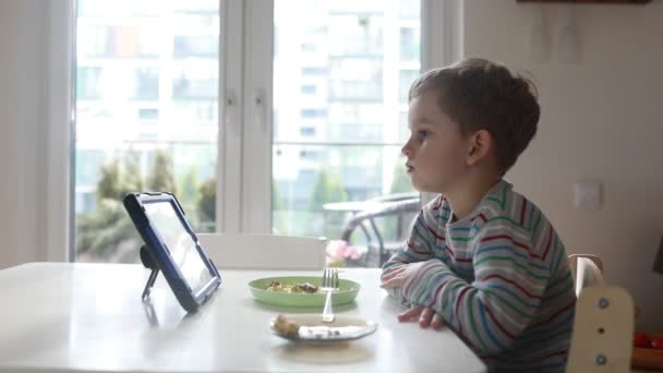 Jeune Garçon Assoit Une Table Cuisine Regardant Attentivement Tablette Pendant — Video