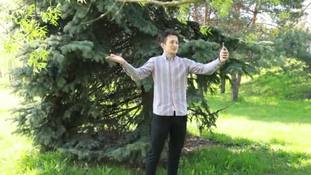 남자가 공원에서 밀집한 에버그린 셀카를 길이에 전화를 햇빛은이의 고요한 분위기를 — 비디오