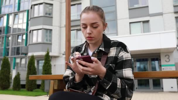 Жінка Сидить Лавці Оточена Мобільним Телефоном Прокручується Через Повідомлення Сповіщення — стокове відео