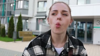 Binanın önünde duran bir kadın komik suratlar yapıyor, yoldan geçenlere eğlence sağlıyor. Yüzlerini çeşitli komik ifadelerle çarpıtıyor. Seyircilerin kahkahalarına neden oluyor..