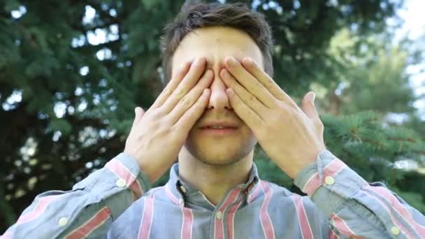 Genç Bir Adam Ormanda Güneşli Yemyeşil Ağaçların Arasında Elleriyle Gözlerini — Stok video