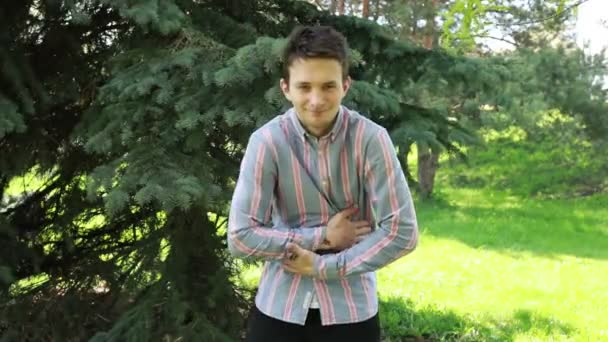 Jeune Homme Vêtu Une Chemise Rayée Décontractée Tient Dans Parc — Video